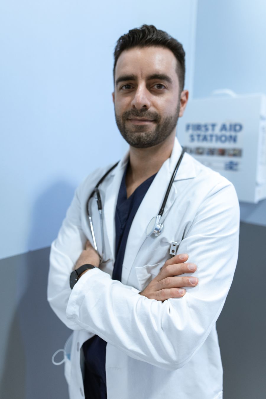 Médico de jaleco branco e estetoscópio, de braços cruzados